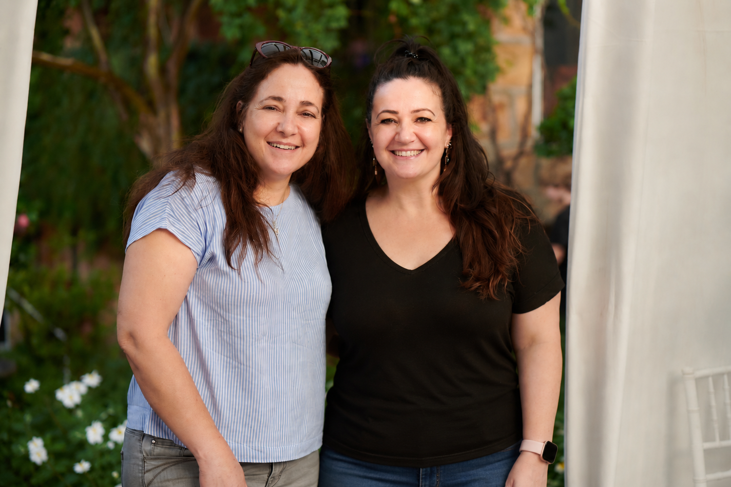 The two sisters who are the owners of AssistAble Living standing together outdoors with a blurred background